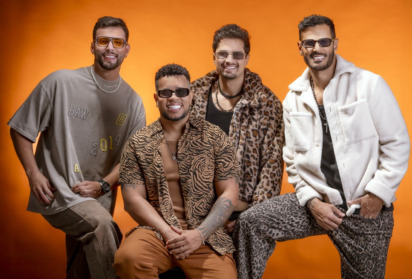 Os quatro integrantes do Deu Samba sentados em fundo laranja